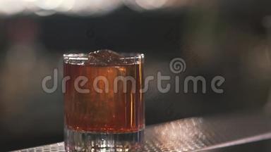 玻璃与美味的冷酒鸡尾酒或威士忌与立方体冰，以清爽的酒吧酒保。 关门